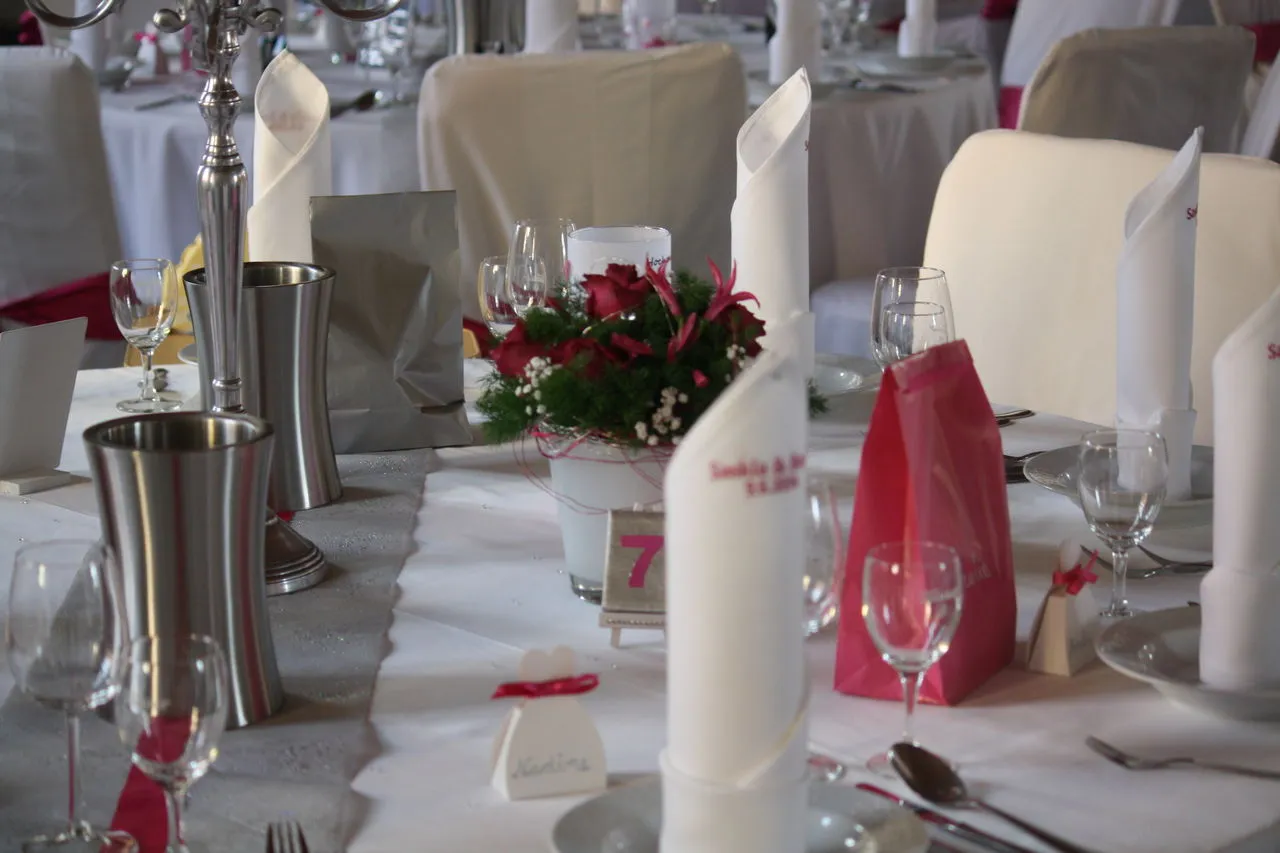 Festtafel mit rotem Blumengesteck, Kerzen und Tischkarten